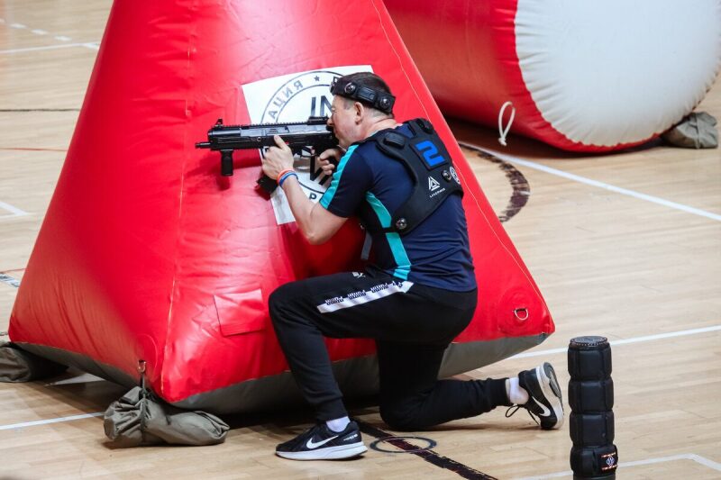 Игрок LASERWAR занимает низкую боевую позицию у красного укрытия.